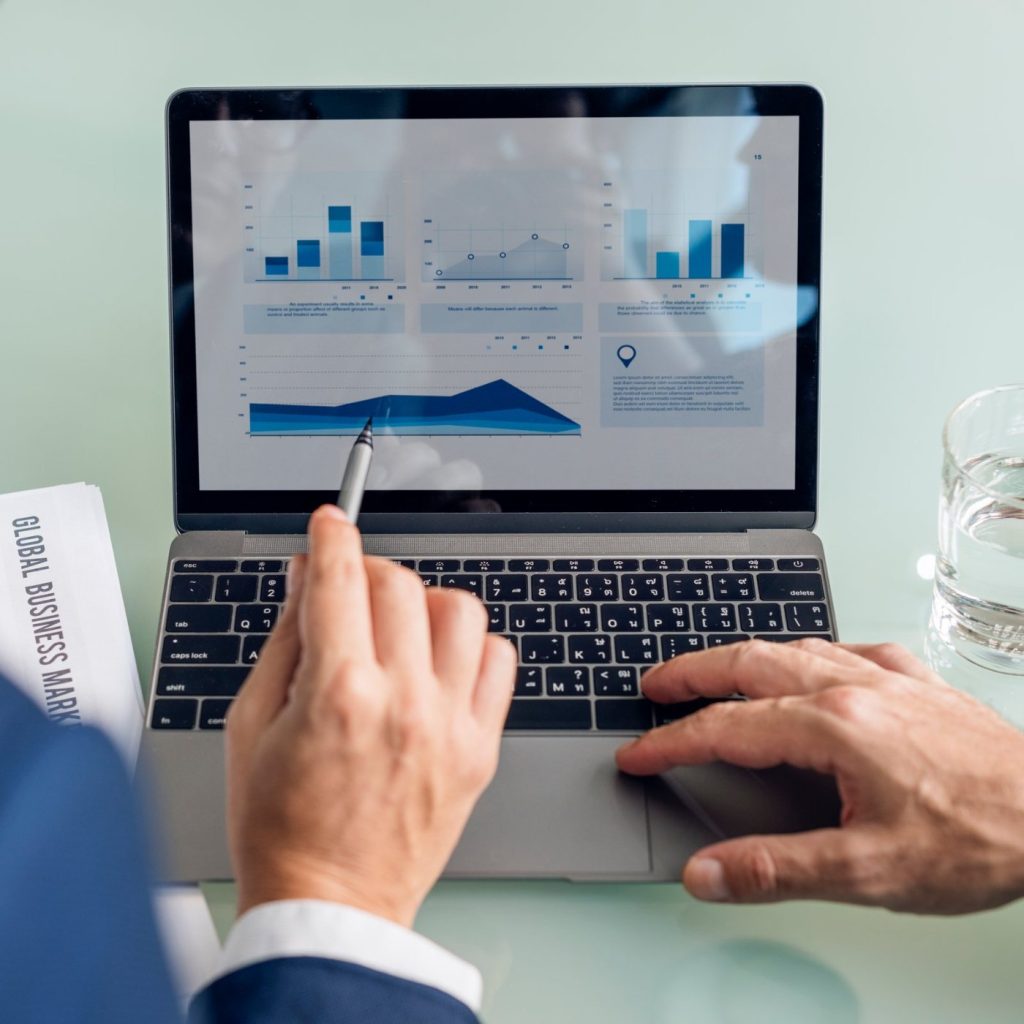 Accountant pointing at charts in a financial report on a laptop screen