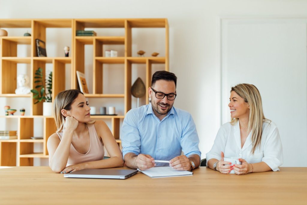 Adviser discussing a business plan with two clients at a wooden table