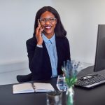Smiling adviser in a suit talking on the phone at her desk