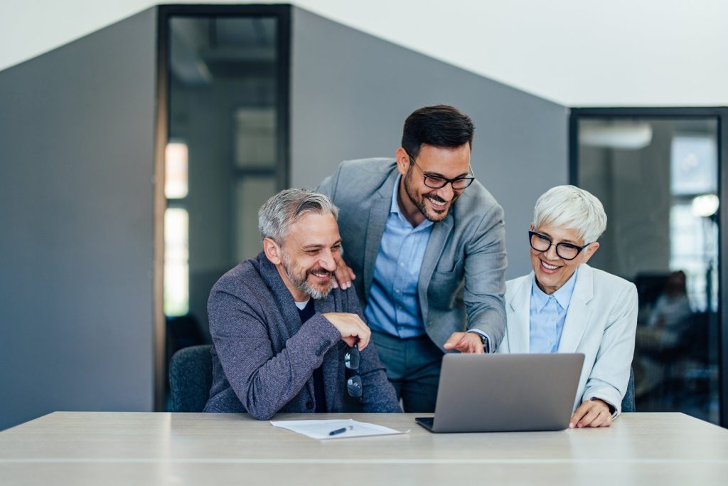 Three accountants reviewing a client report on a laptop in a modern office